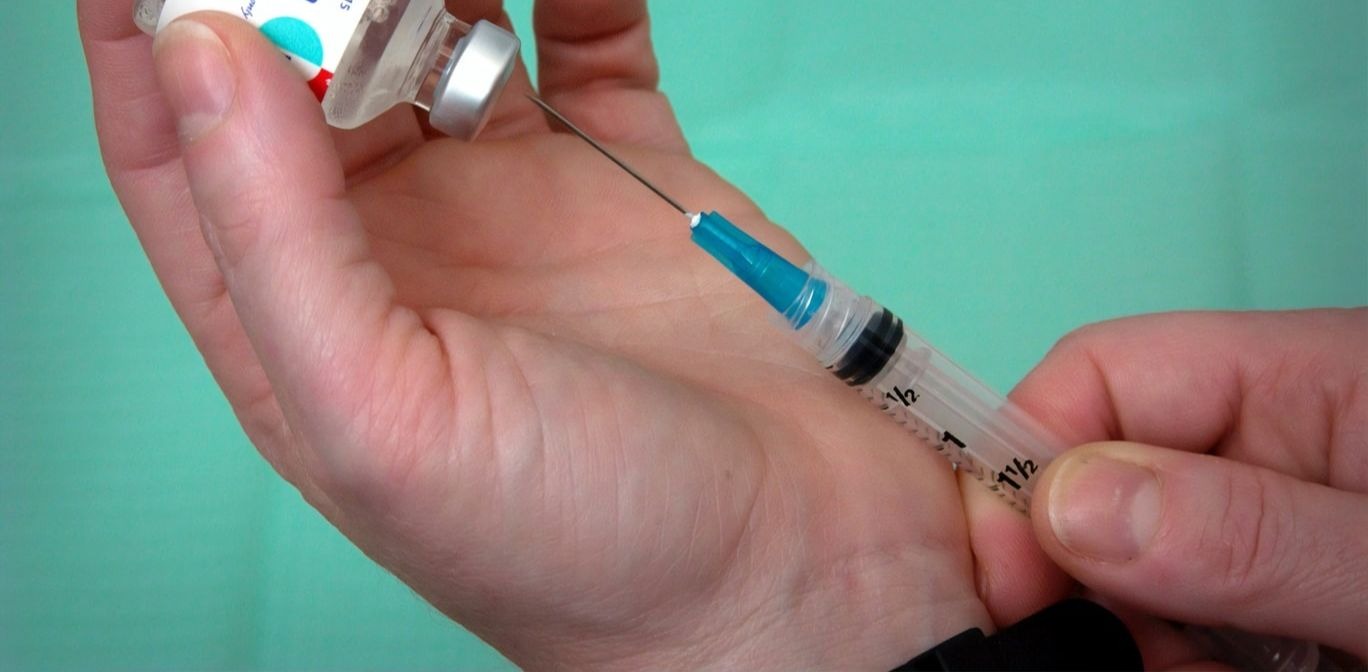 Une personne injectant un produit dans une séringue.
