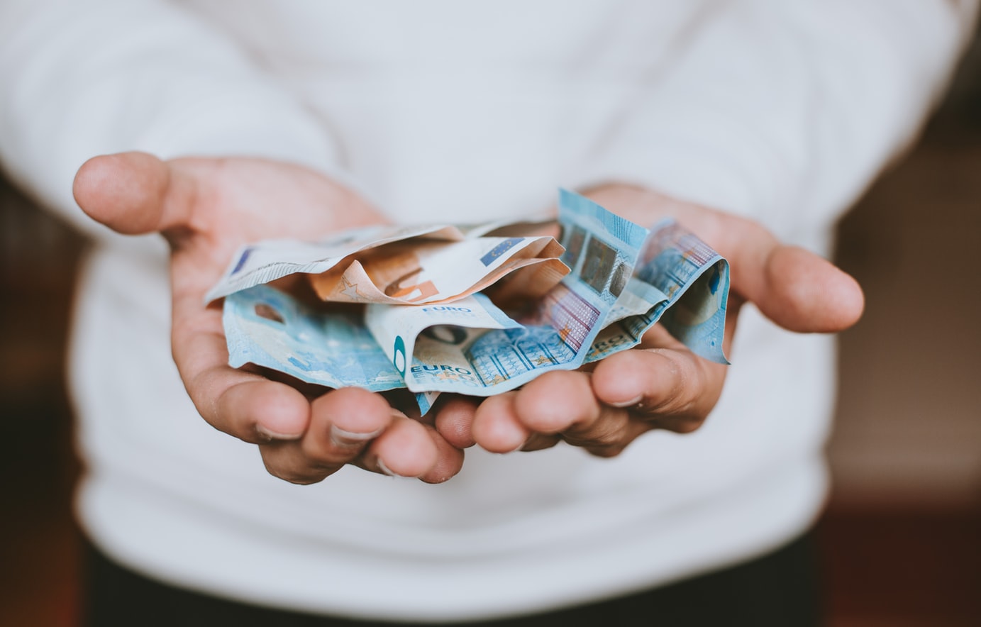 Un homme tenant des billets d'euro.